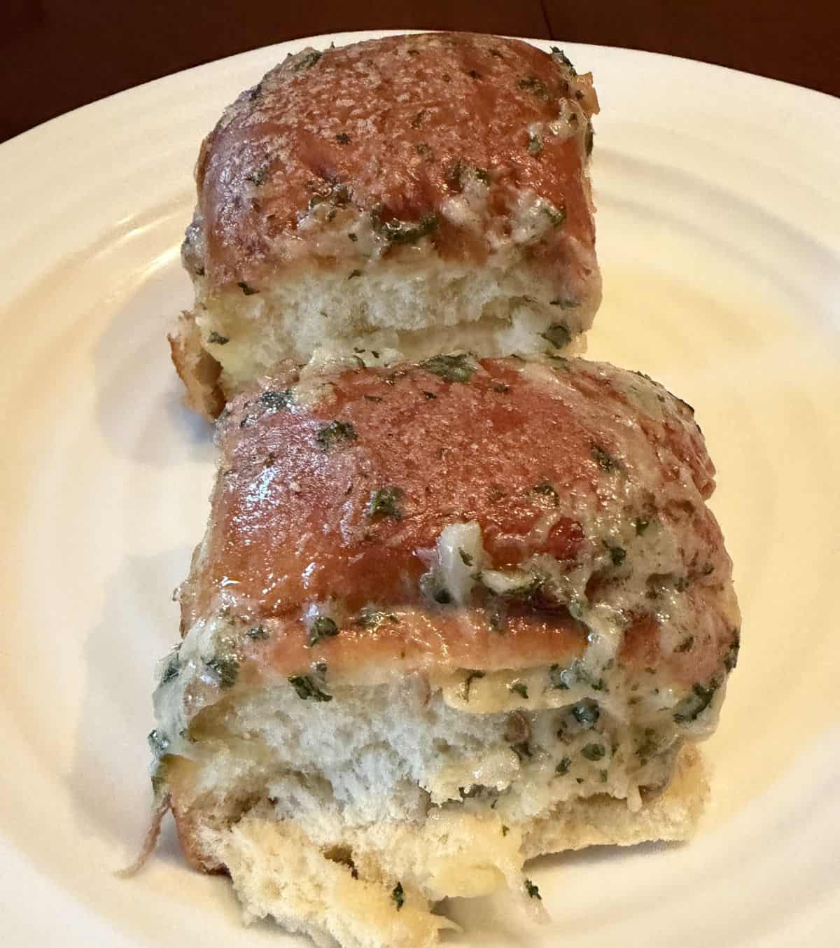 Image of two brioche garlic buns heated and served on a white plate.