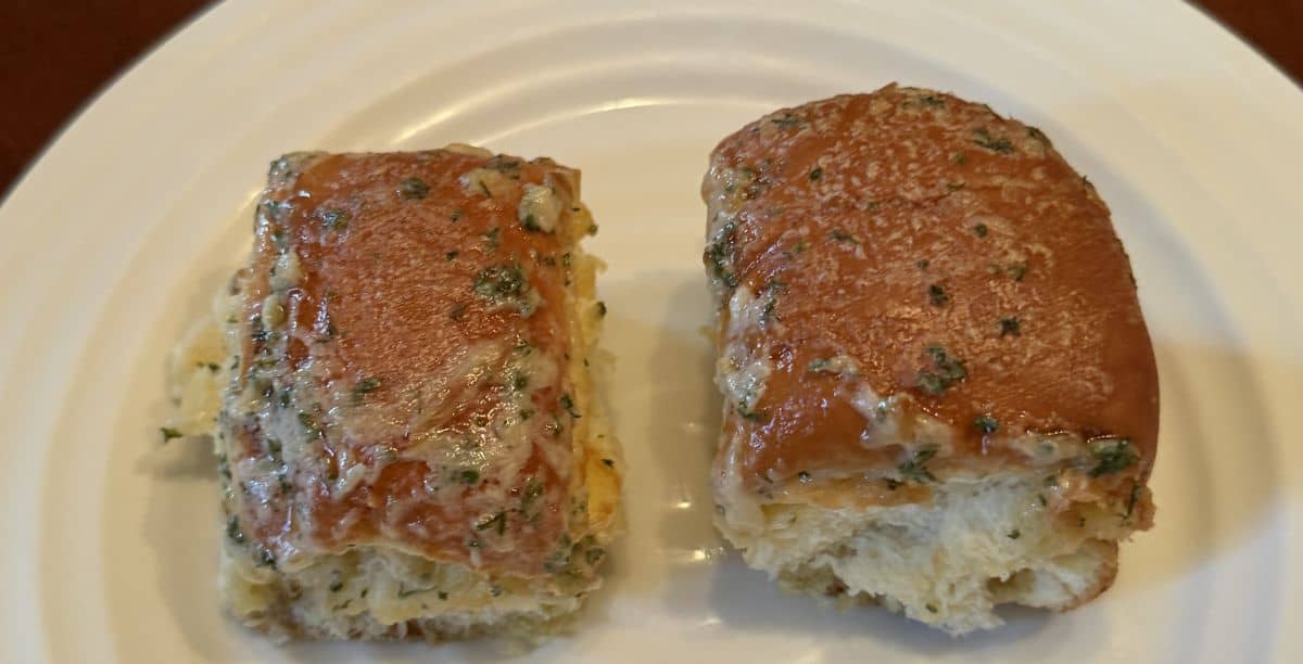 Image of two brioche garlic buns heated and served on a white plate.