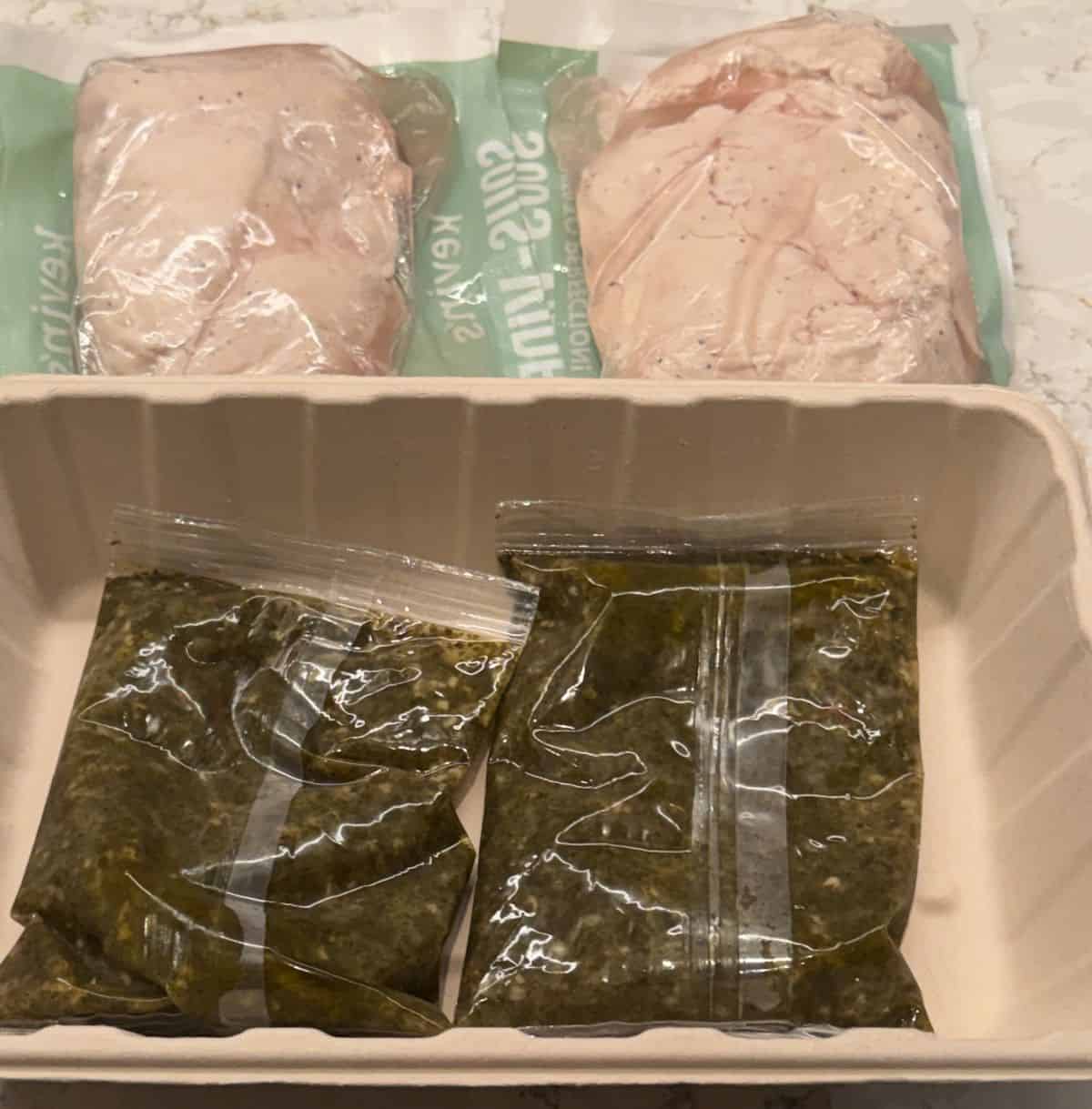Image of the cilantro lime chicken package contents sitting on a table. There are two pouches of sauce and two pouches of chicken.