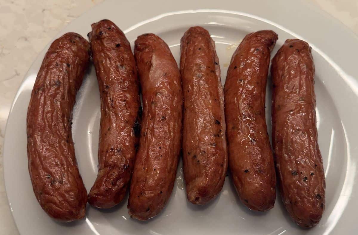 Image of six grilled chicken sausages served on a white plate.