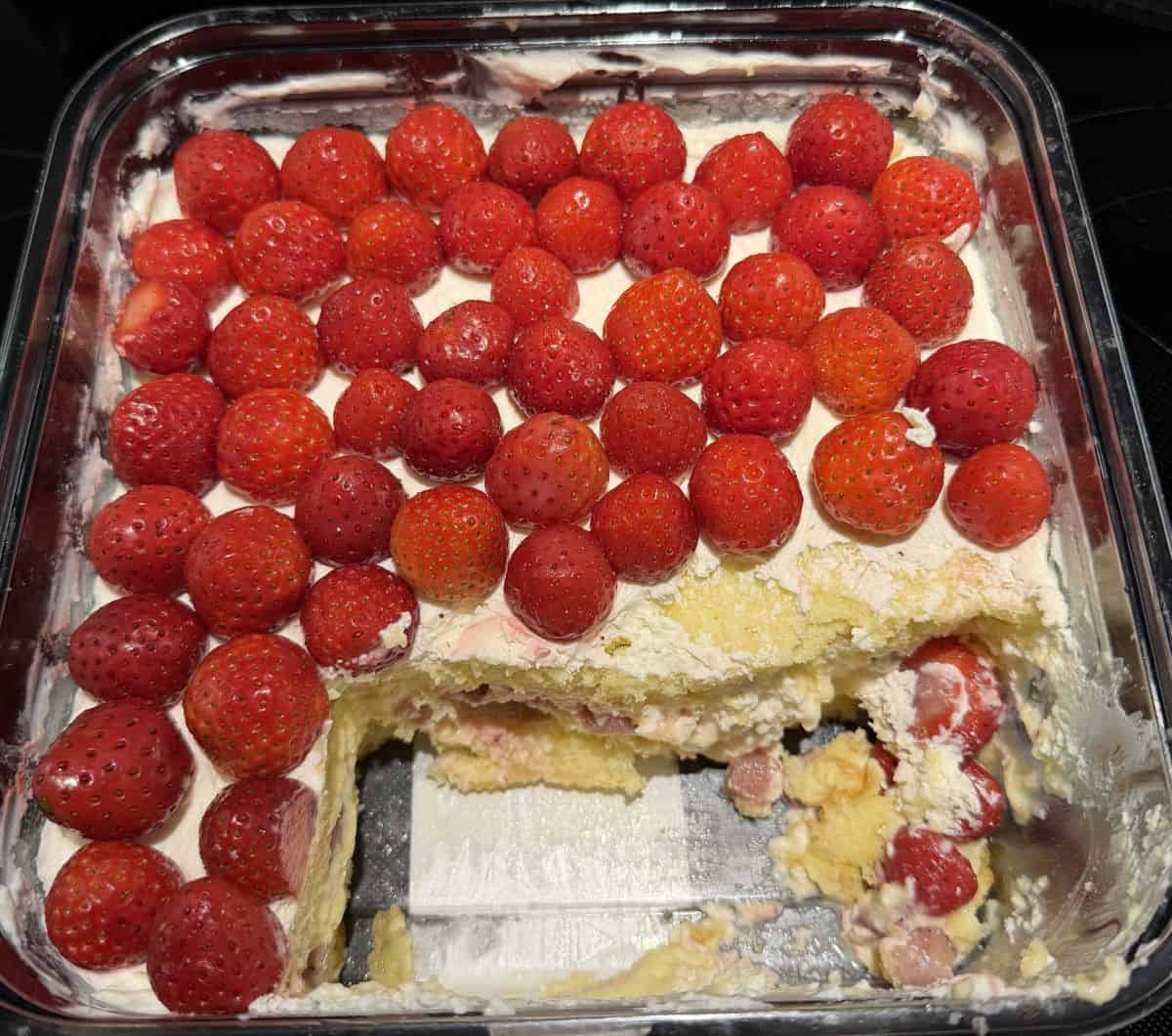 Image of the opened strawberry scoop cake sitting on a table with a few scoops taken out of it.