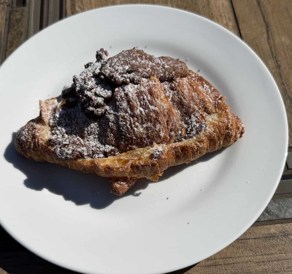 Image of one twice baked chocolate filled croissant served on a white plate.