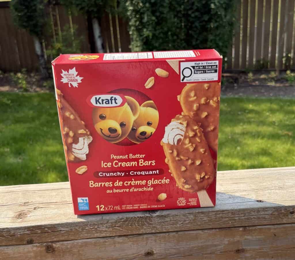 Image of the Costco Kraft Peanut Butter Ice Cream Bars box sitting on a table outside unopened with trees and grass in the background.