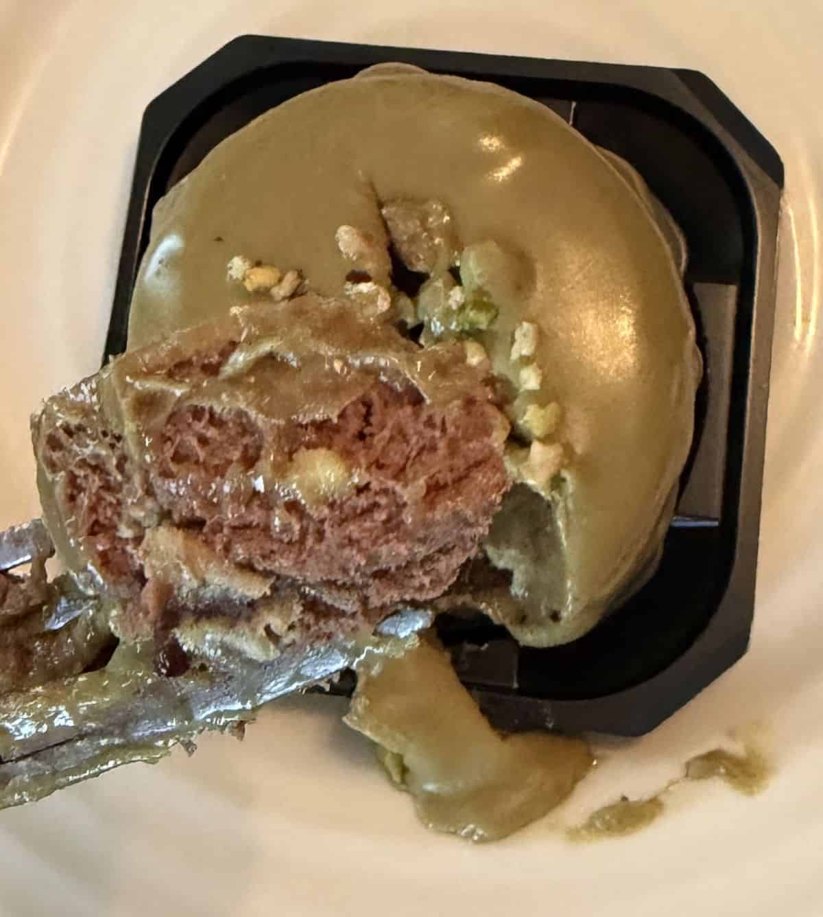 Top down image of a fork with chocolate pistachio mousse on it hovering over a pistachio mousse.