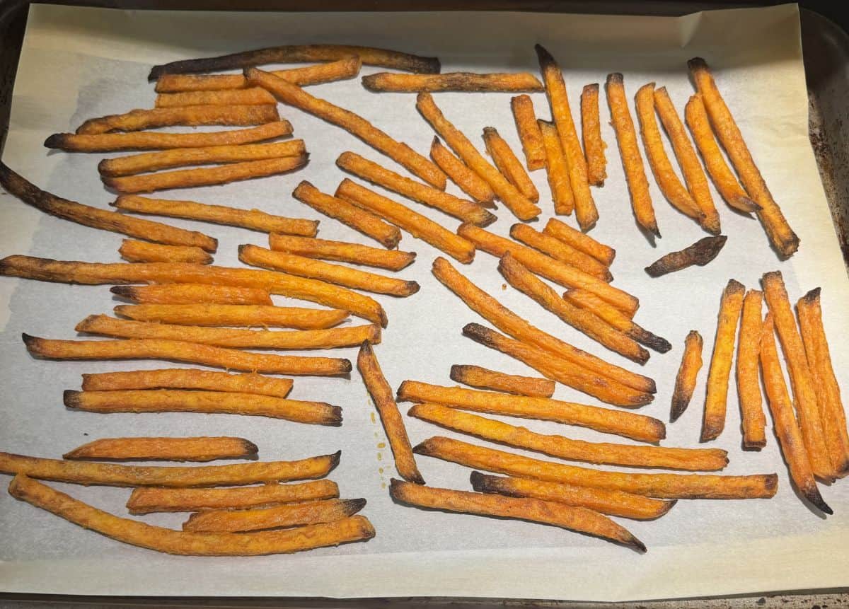 Image of the sweet potato fries on a parchment lined cookie sheet after being baked in the oven.