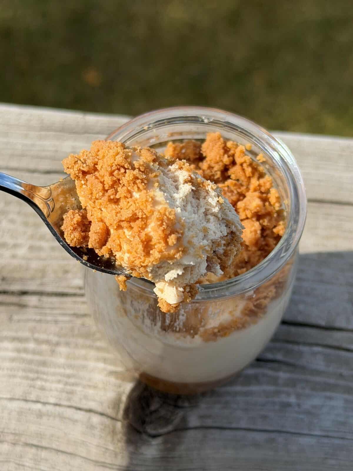 Closeup image of spoonful of mousse hovering over a mousse that's sitting on a deck outside.