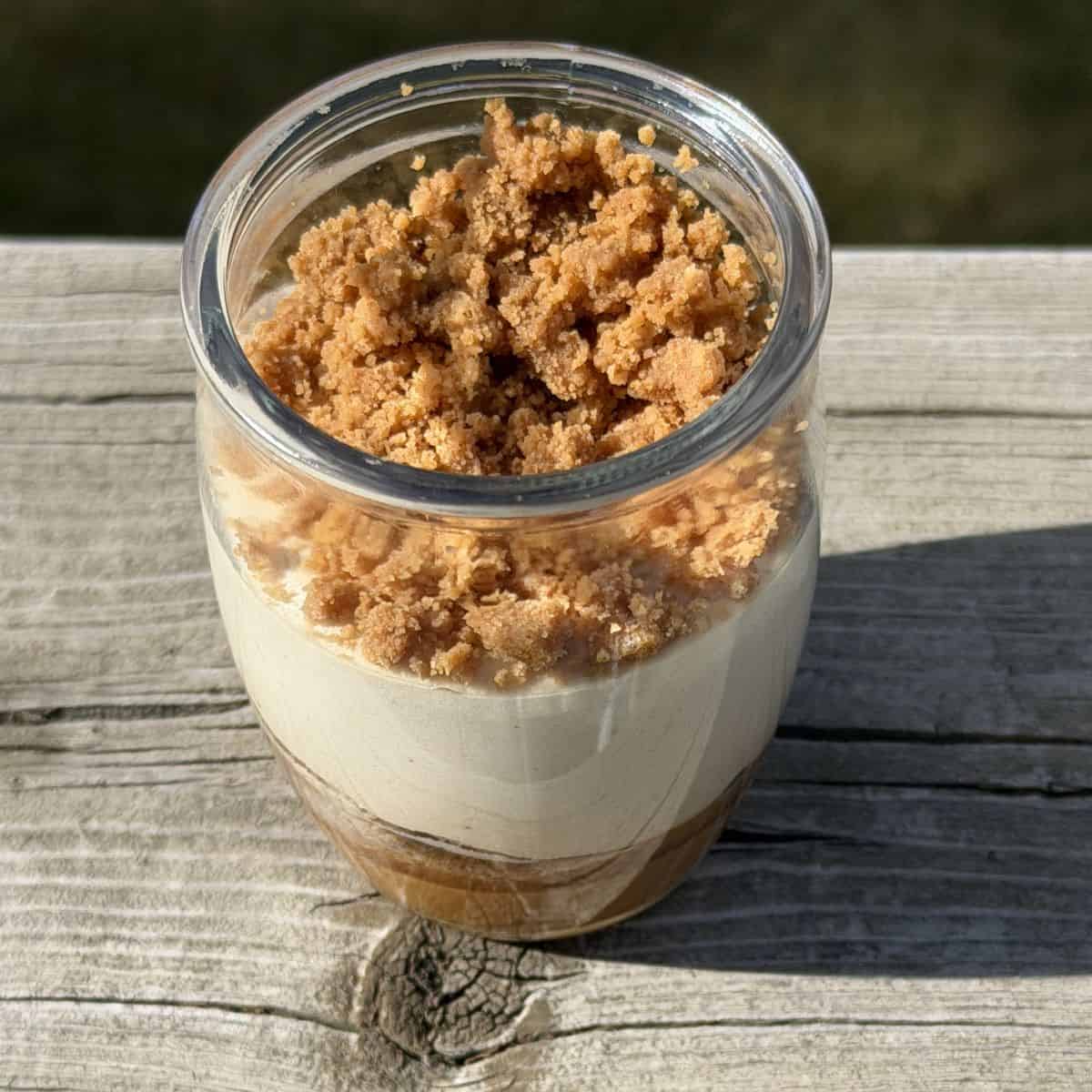 Top down close up image of one cookie butter mousse with the lid off sitting on a deck outside.