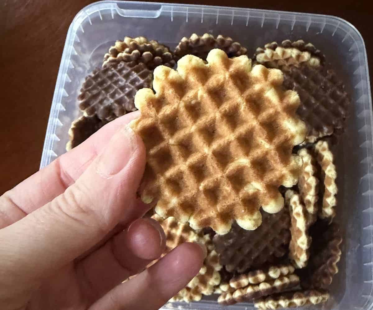 Image of a hand holding one biscuit waffle side up close to the camera.