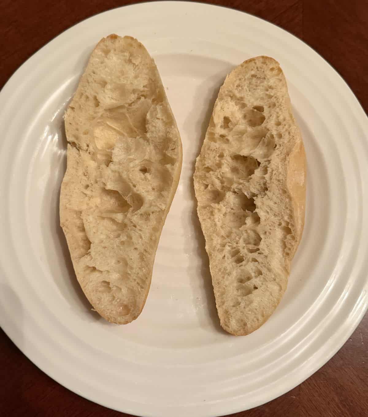 Image of one crusty roll cut in half so you can see the inside of the roll.