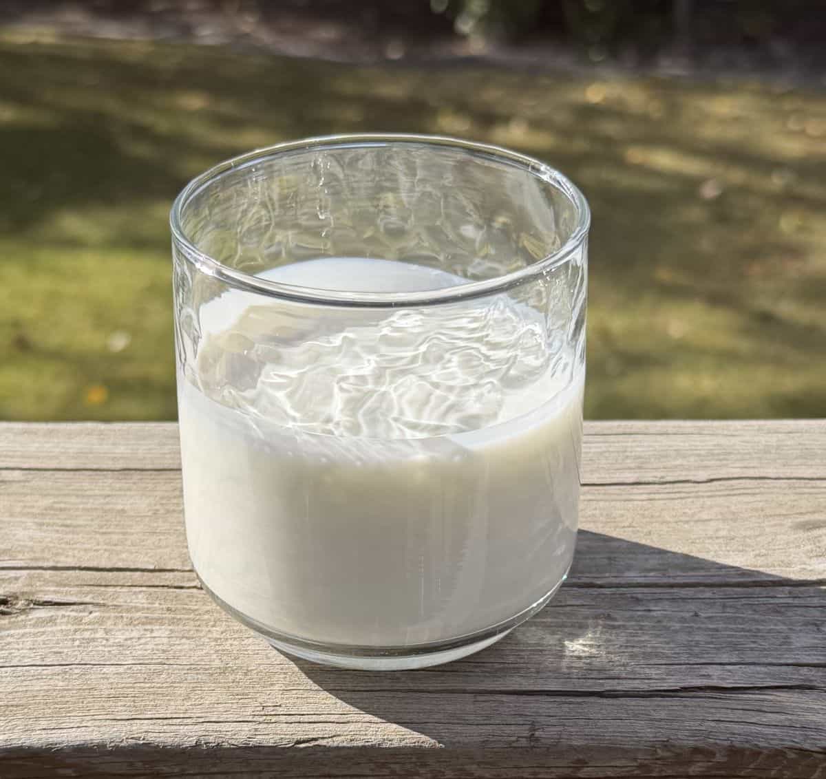 Image of a glass of kefir sitting on a porch outside.
