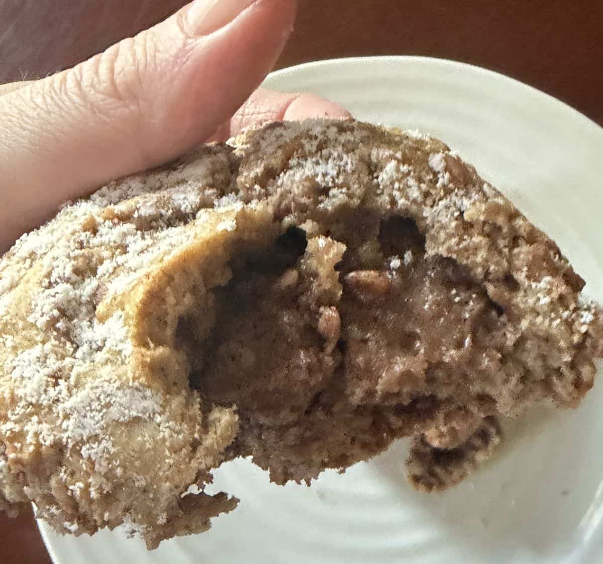 Image of the Filled Cinnamon Scone being held in a hand over a plate. It's been cut in half so you can see the filling.