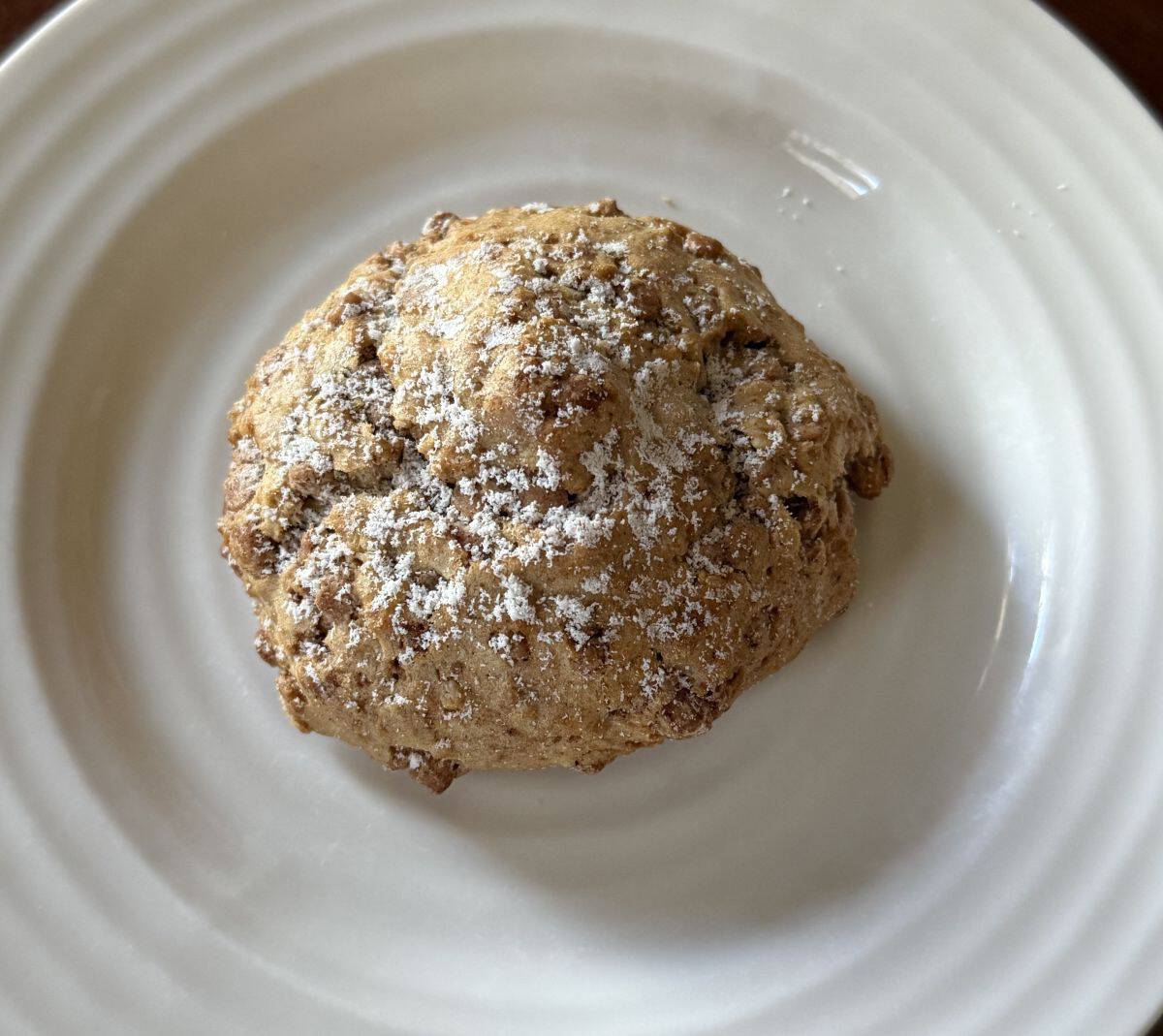 Top down image of one filled cinnamon scone served on a white plate.