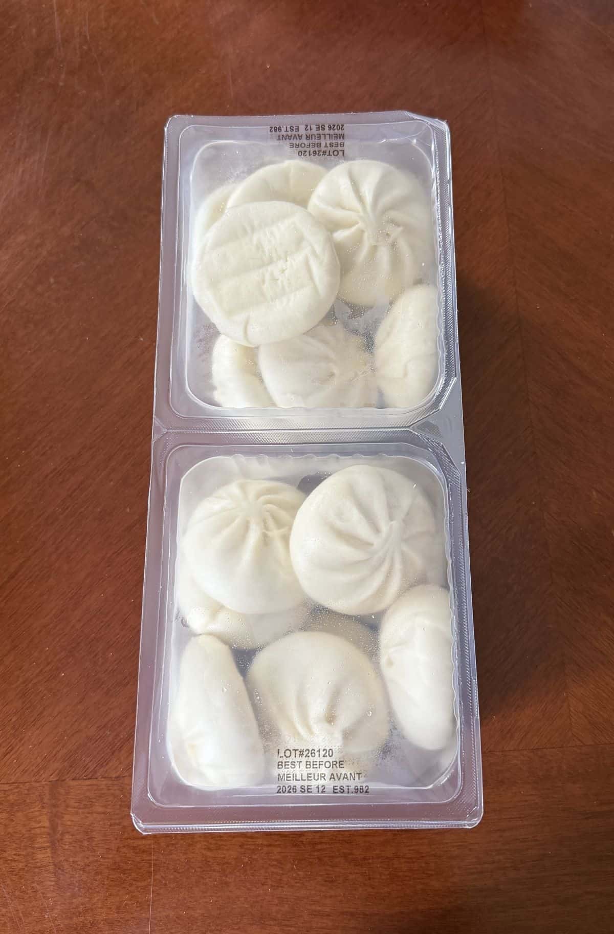 Image of two unopened plastic packages with uncooked pork bao buns in the packages.
