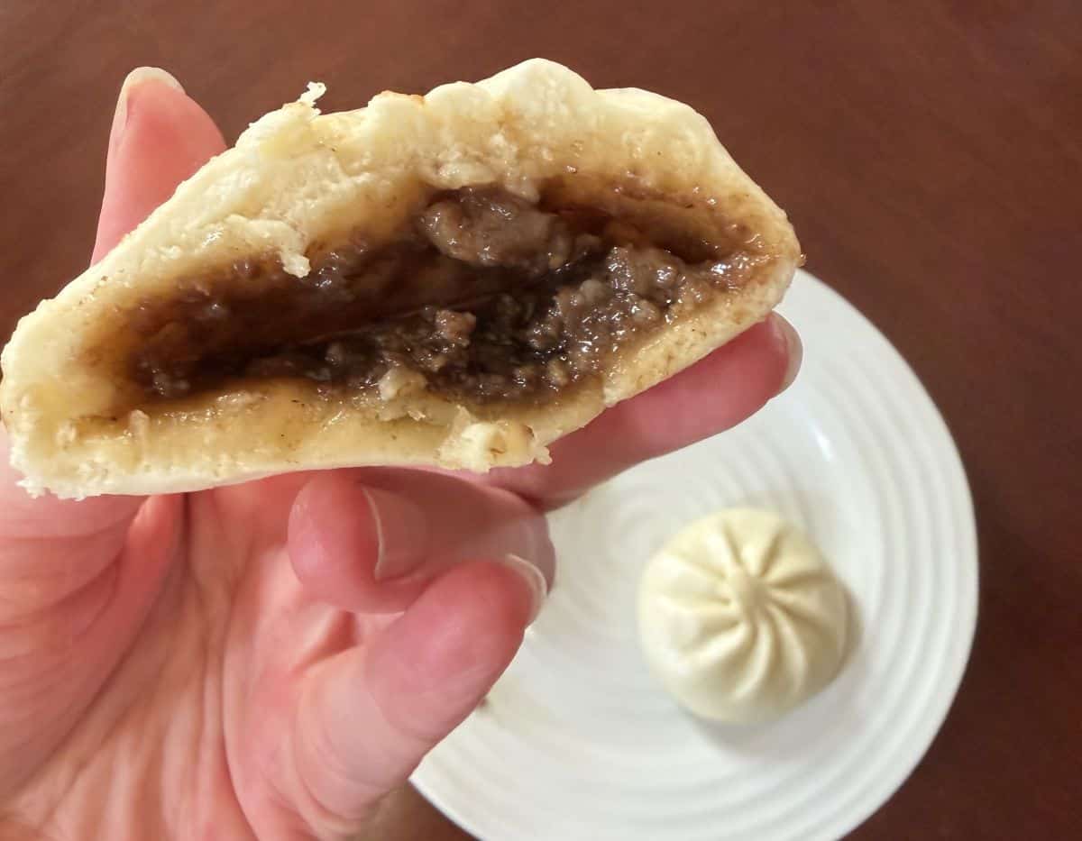 Image of one pork bao bun that's been cut in half so you can see the pork filling.