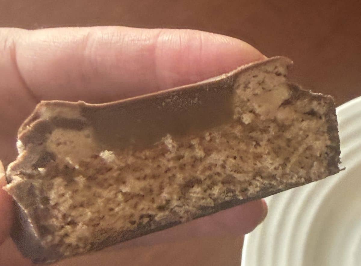 Image of a hand holding the mini cake with a few bites taken out of it so you can see the filling/middle.
