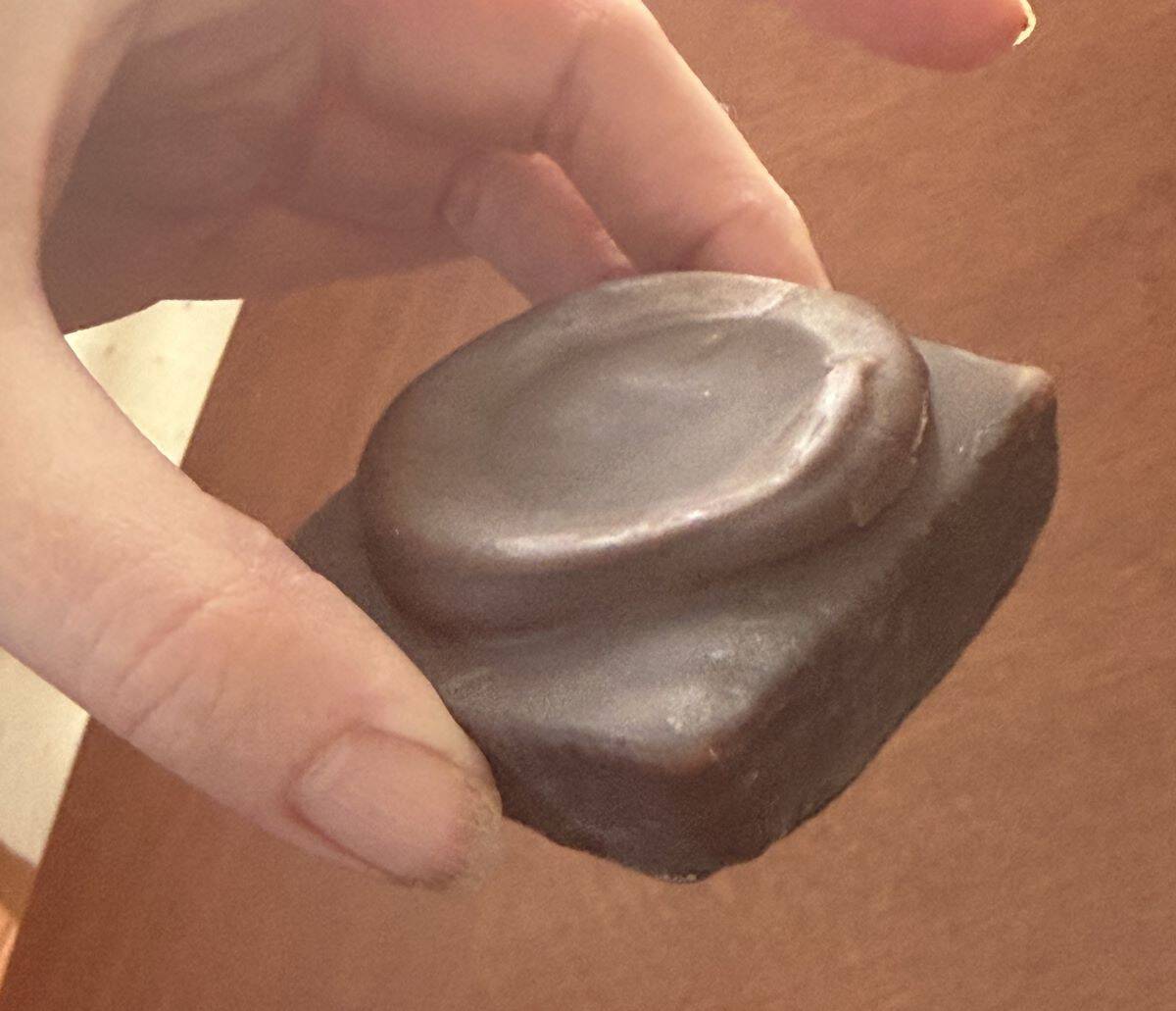 Closeup image of a hand holding a mini cake close to the camera.