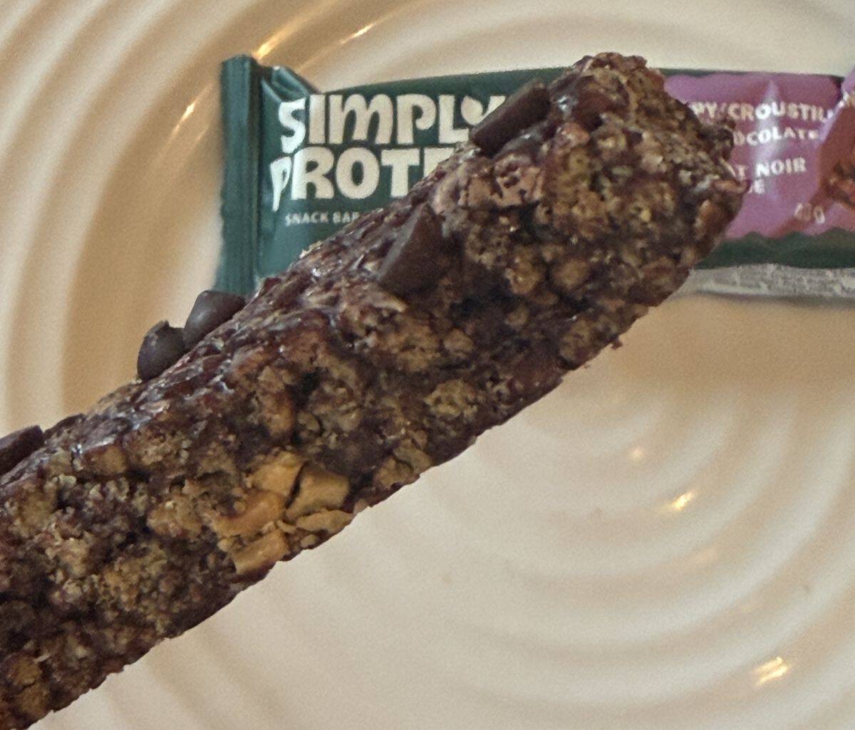 Closeup image of a hand holding one dark chocolate almond bar close to the camera.