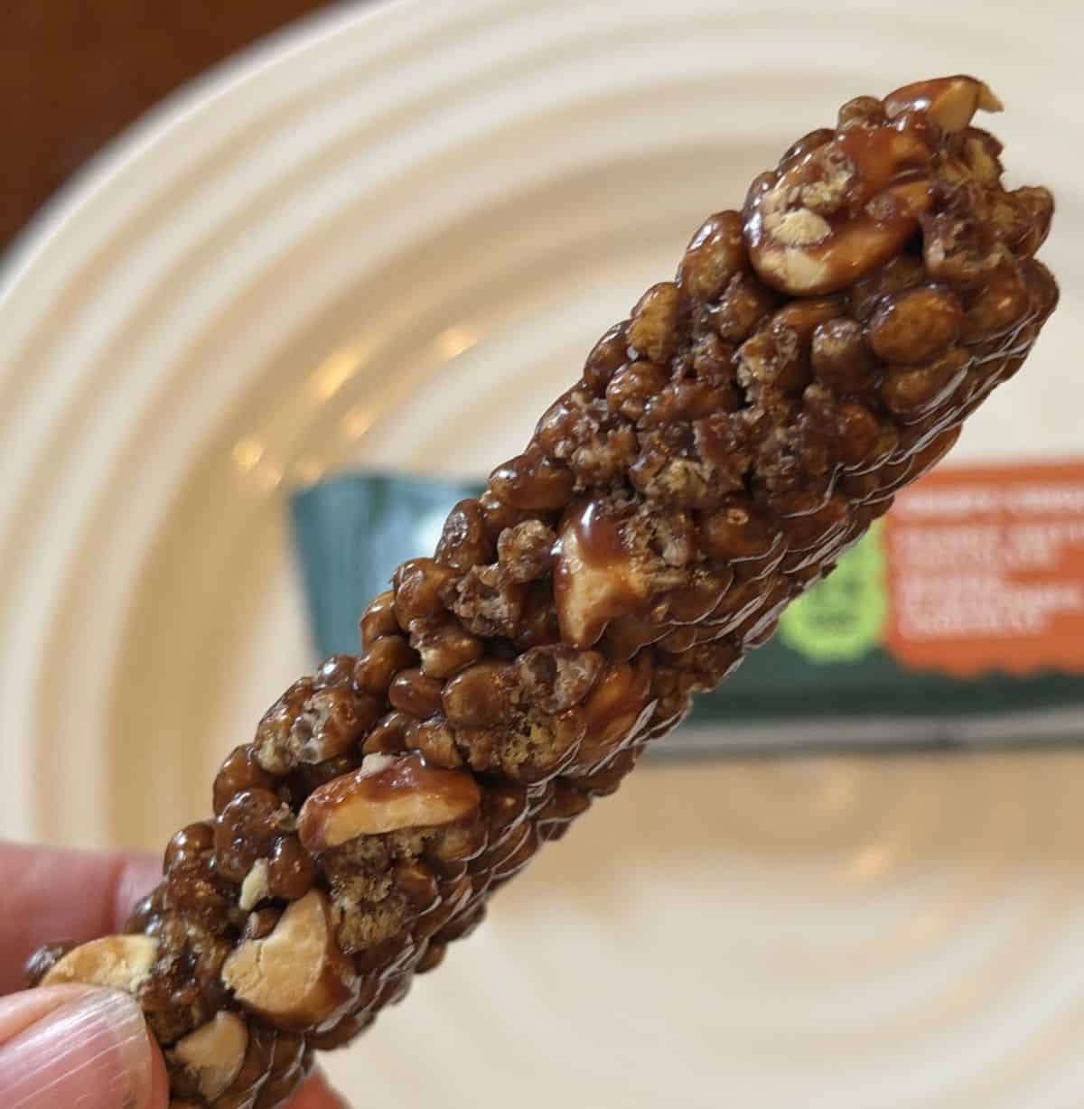 Closeup image of a hand holding one peanut butter chocolate bar close to the camera.