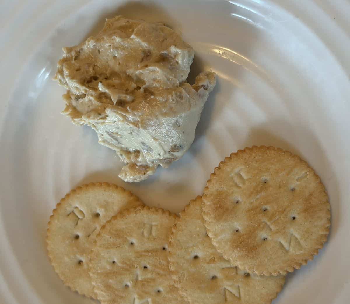 Closeup top-down image of a serving of dip on a white plate.
