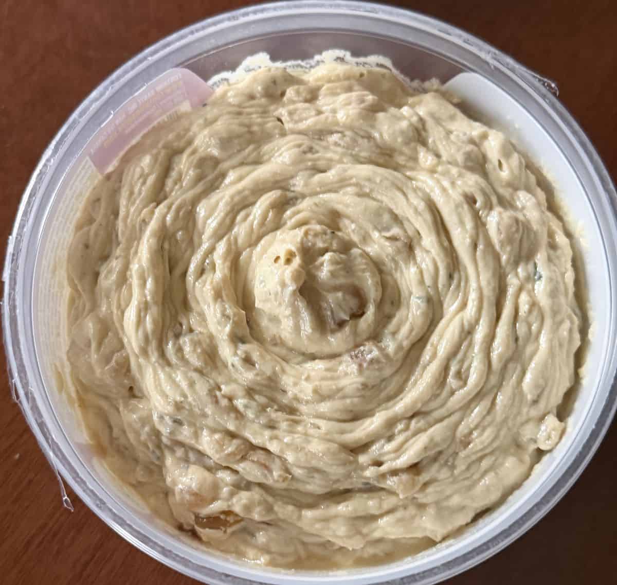 Top-down image of an open container of Costco Fontaine Sante Caramelized Onion Dip with Boursin sitting on a table.