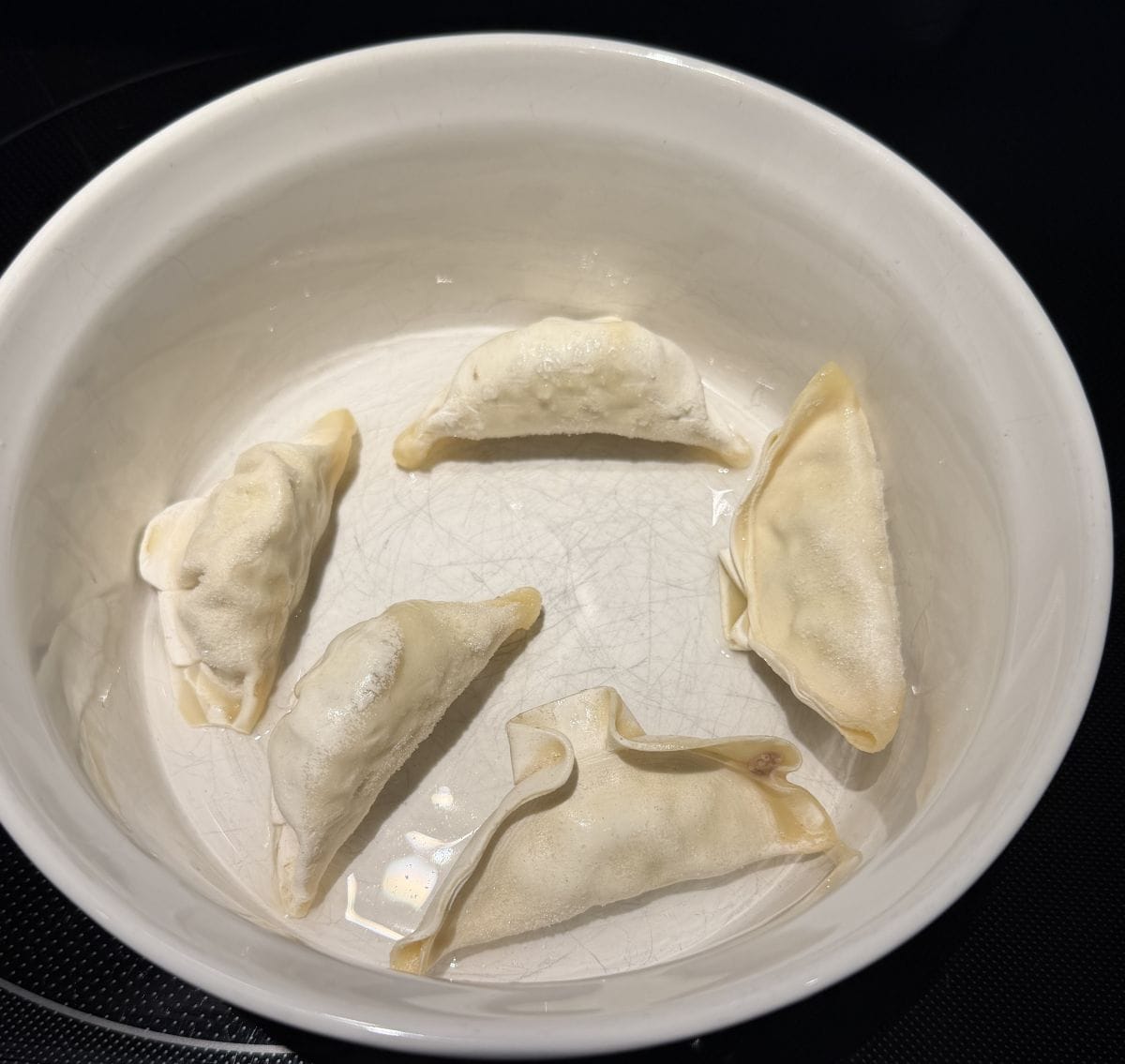 Image of frozen gyoza in a microwave safe dish ready to cook.