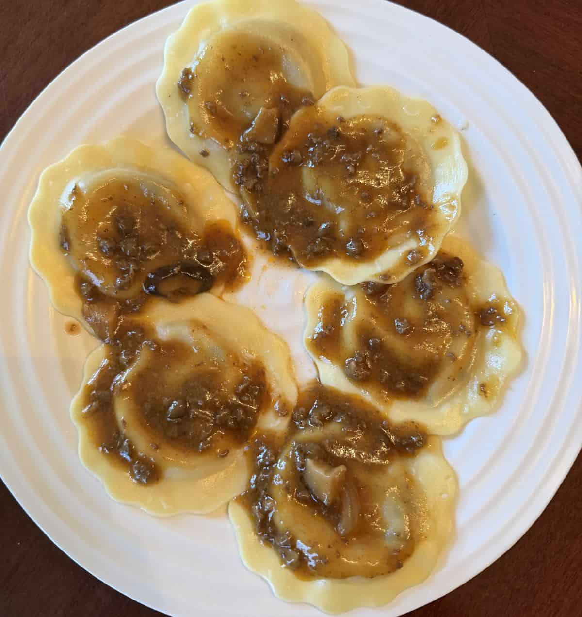 Image of the ravioli with sauce cooked and served on a white plate.